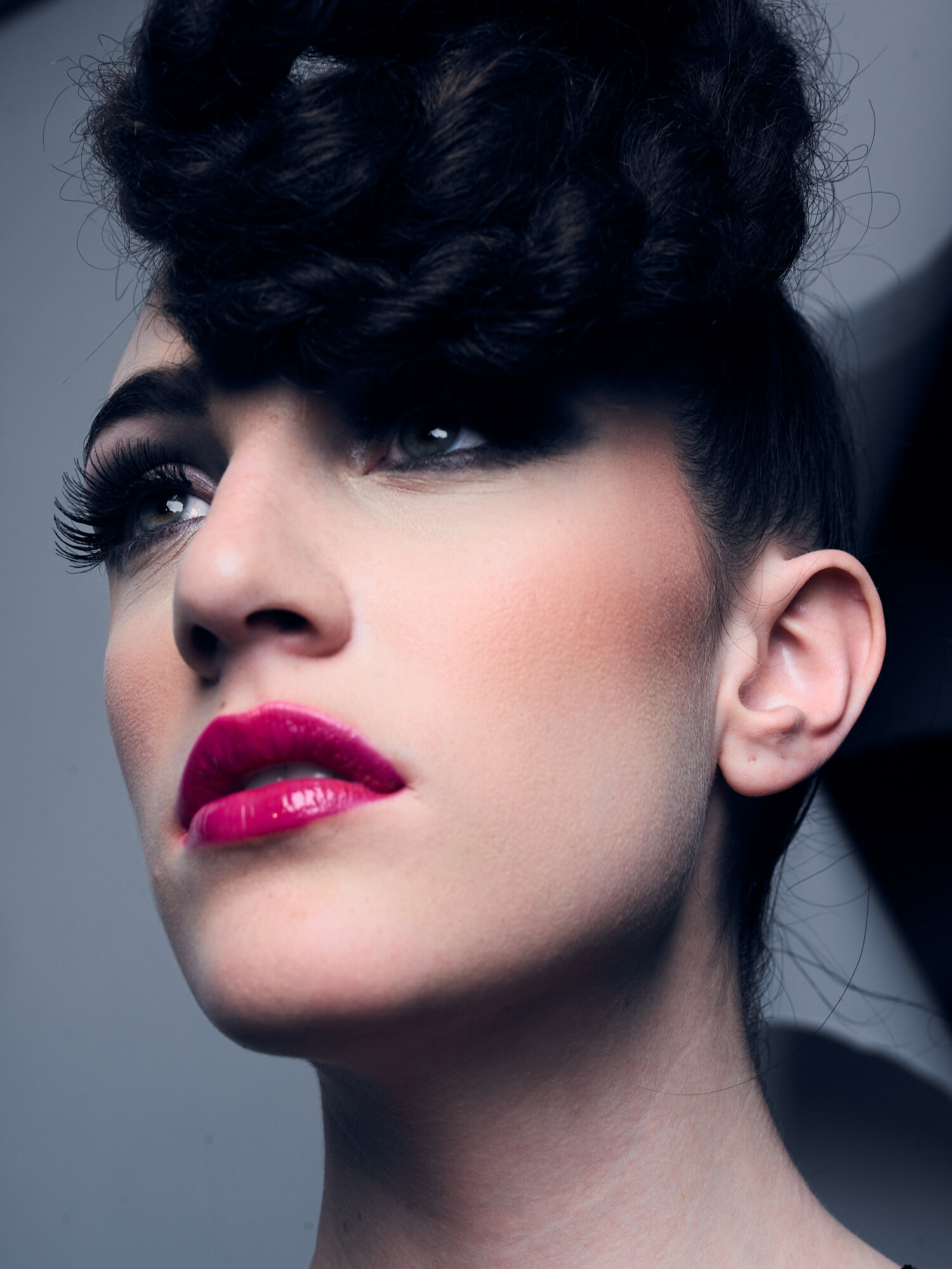High-fashion beauty close-up with voluminous textured hair, dramatic lashes, and glossy bold pink lips, studio lighting. Beauty photography by Jason Guffy.