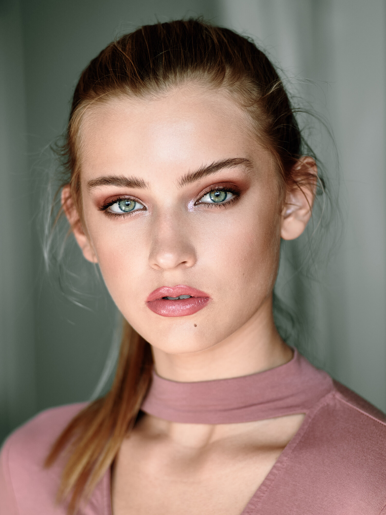 Studio beauty portrait with bold red eyeshadow and green eyes, editorial close-up. Beauty photography by Jason Guffy.