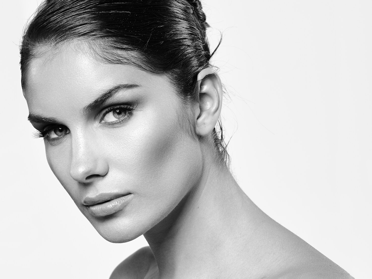 Clean black and white beauty close-up, natural skin and minimal styling, direct gaze. Beauty photography by Jason Guffy.