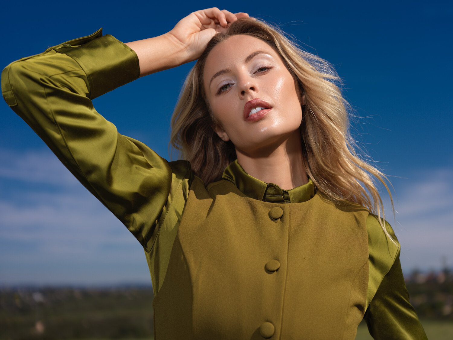 Natural-light beauty editorial on a hilltop, dewy skin and a glossy lip in olive satin, Southern California. Beauty photography by Jason Guffy.