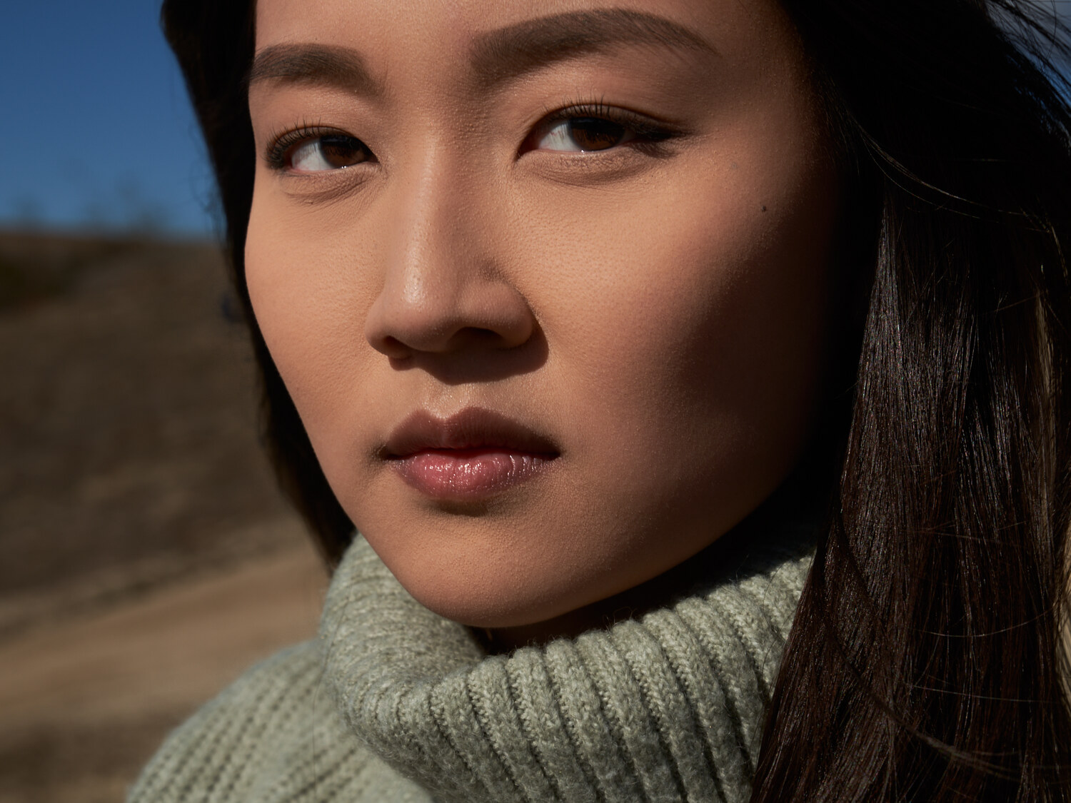 Outdoor beauty close-up in natural light, ribbed turtleneck and a calm focused expression, Southern California. Beauty photography by Jason Guffy.