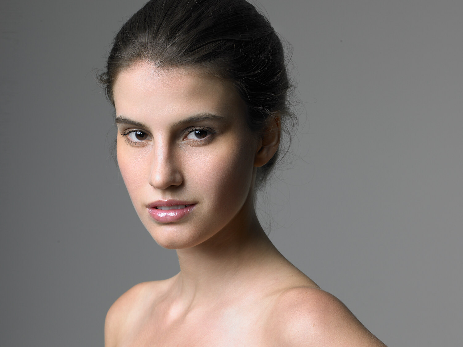Studio beauty portrait in soft light, natural glam with dewy skin and a glossy lip, grey seamless. Beauty photography by Jason Guffy.
