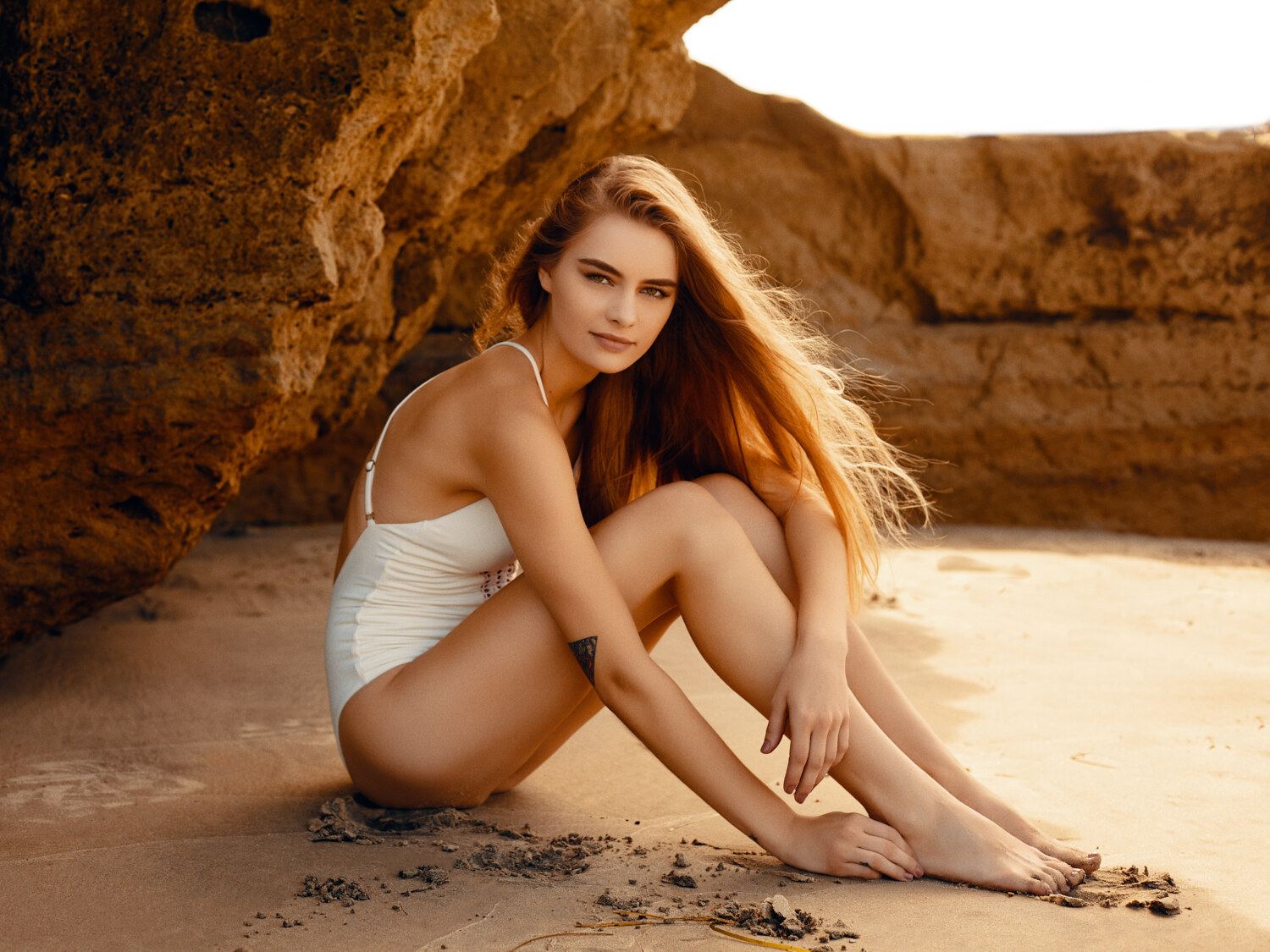 Beach swimwear editorial in natural light on the rocks at Del Mar, California, white swimsuit. Swimwear photography by Jason Guffy.