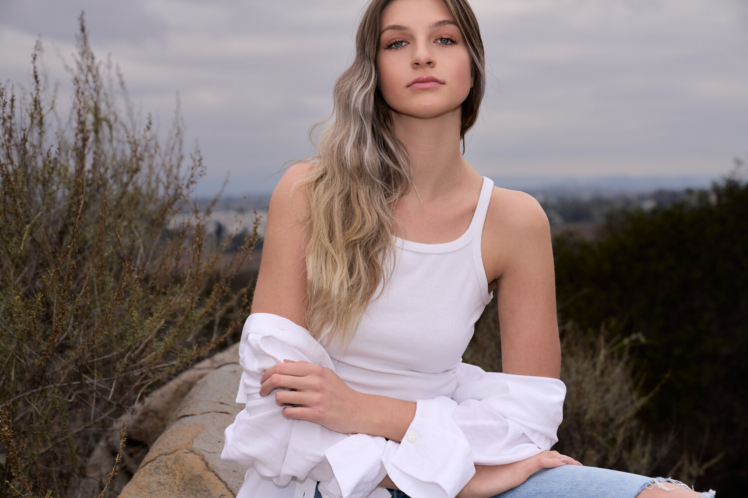 Natural-light fashion lifestyle portrait on a coastal hillside in Carlsbad, California, white tank and denim. Fashion photography by Jason Guffy.