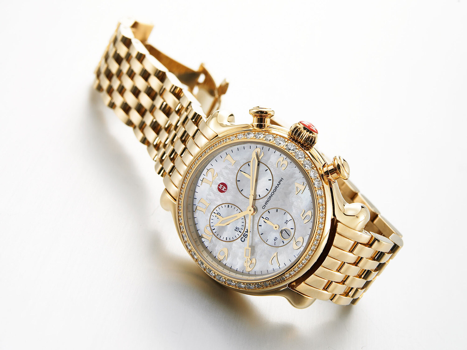 Michele gold chronograph watch with a mother-of-pearl dial and diamond bezel on a white background. Product photography by Jason Guffy.
