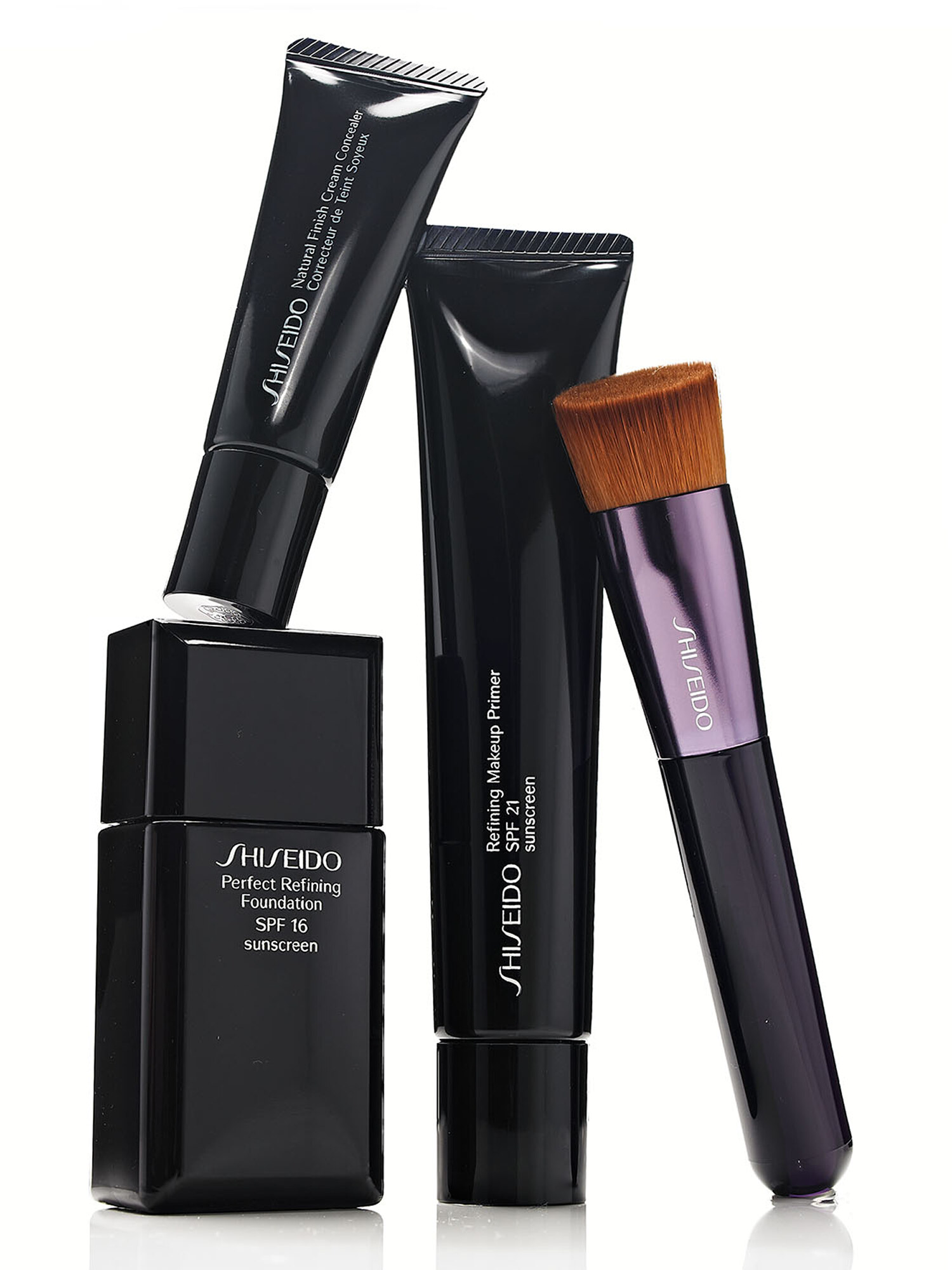 Shiseido foundation, primer, and concealer with a foundation brush on a white background. Beauty product photography by Jason Guffy.