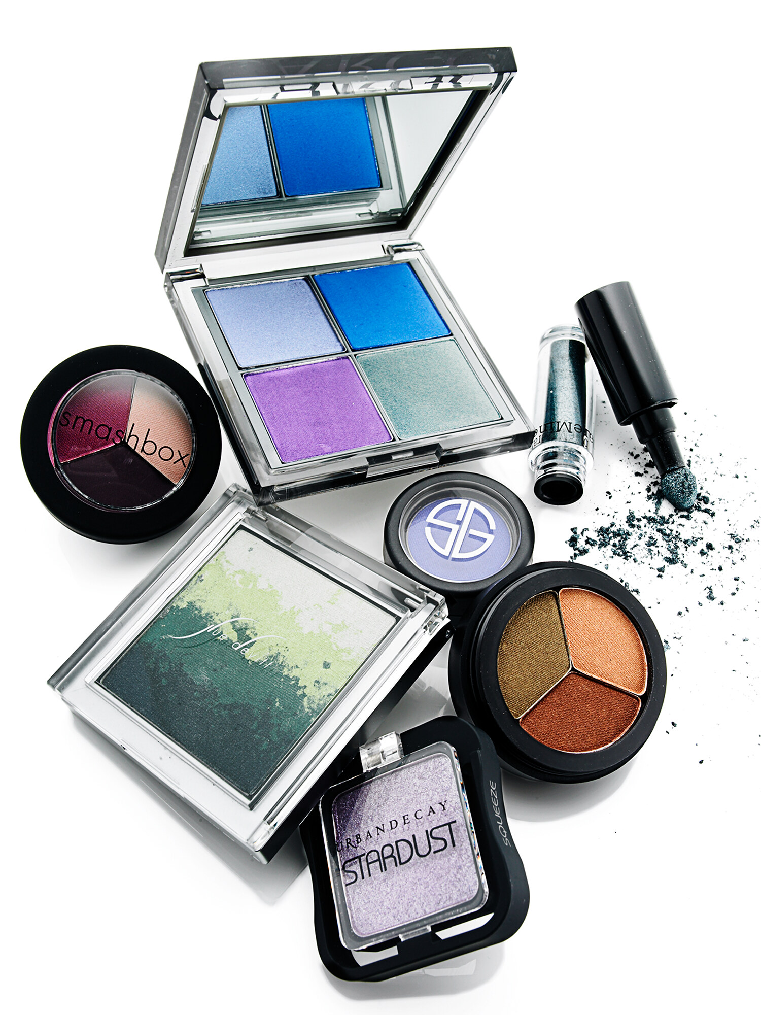 Editorial cosmetics flatlay of eyeshadow palettes and pigments from Smashbox and Urban Decay on white. Beauty product photography by Jason Guffy.