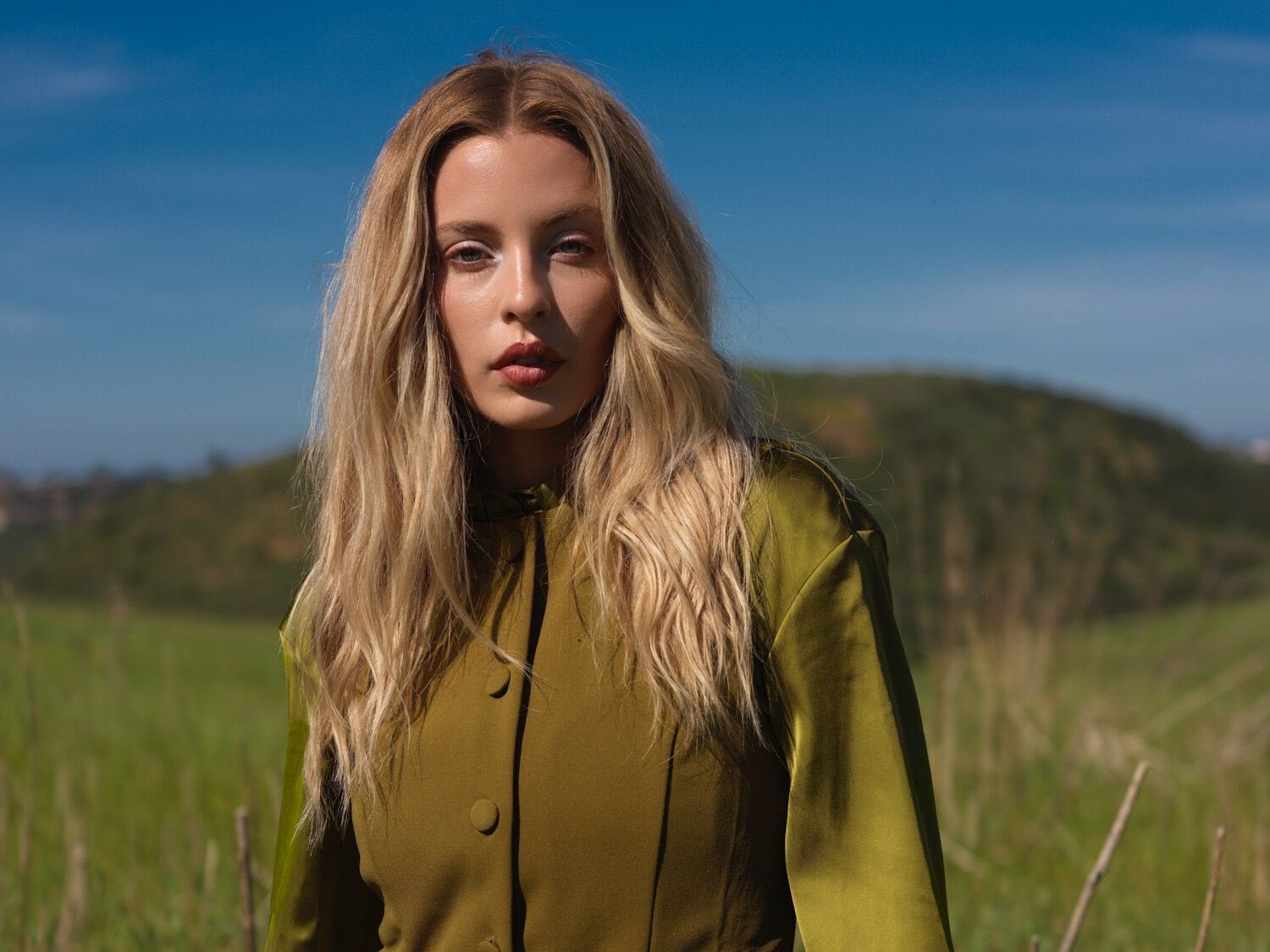 Fashion lifestyle editorial, a close with windblown hair in a grass field, natural daylight. Fashion photography by Jason Guffy.