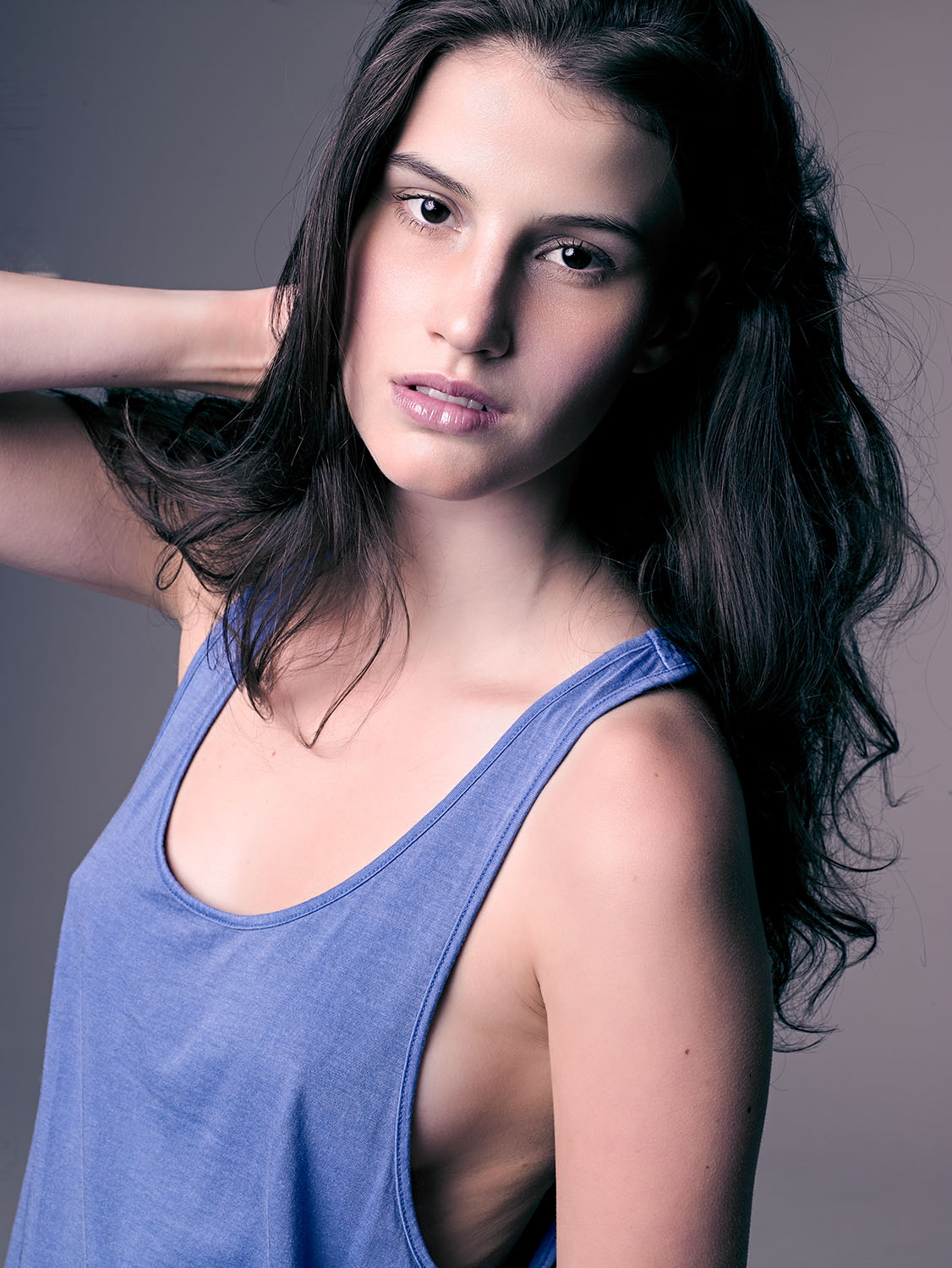 Comp card image of model Liz Kelley with natural makeup, soft expression, and studio lighting, wearing a blue tank top for portfolio