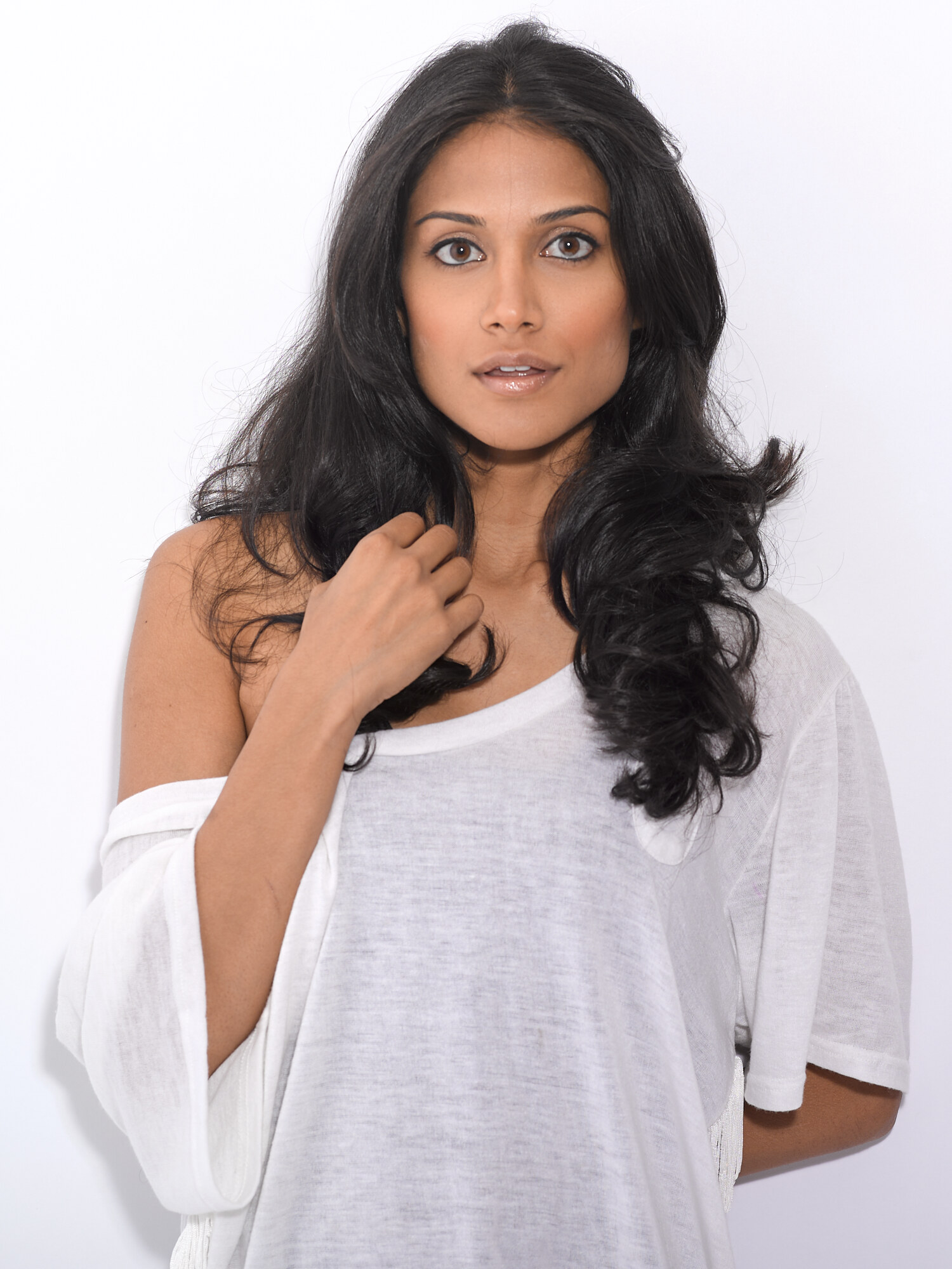 Studio headshot of actress Melanie Chandra in a white off-shoulder top, natural makeup, voluminous hair. Portrait photography by Jason Guffy.